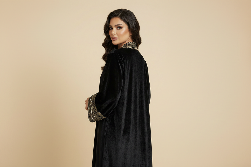Woman wearing a black velvet coat with intricate detailing on a beige background